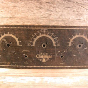 May include: A vintage wooden radio panel with three circular gauges and the text "NEW CLARODYNE" in gold lettering.