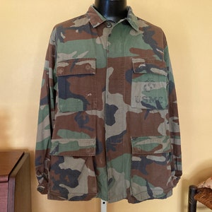 May include: A camouflage utility jacket with a button-up front and multiple pockets. The jacket has a USMC patch on the right pocket.