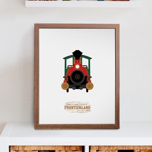 May include: A framed print of a red and green train engine with black wheels and a black smoke stack. The text "FRONTIERLAND" is printed below the train in a brown font.