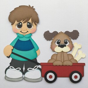 May include: A paper cutout of a boy pulling a red wagon with a brown dog inside. The boy wears a teal shirt, gray pants, and black shoes. The dog has a bone in the wagon.
