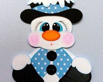 May include: A whimsical snowman cutout with a white body, blue polka-dot vest, and a black hat. The snowman has an orange nose, rosy cheeks, and large blue eyes. The hat is topped with a white snow-like design. Black boots complete the look.