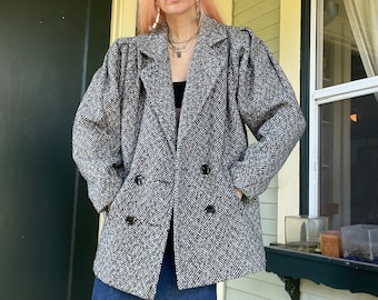 May include: A black and white herringbone patterned double-breasted coat with puffed sleeves.