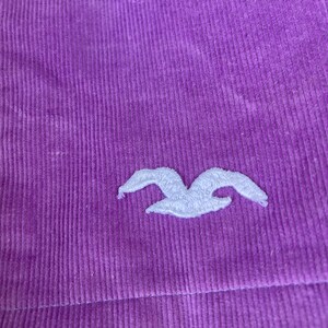 May include: Purple corduroy fabric with a white embroidered seagull logo.
