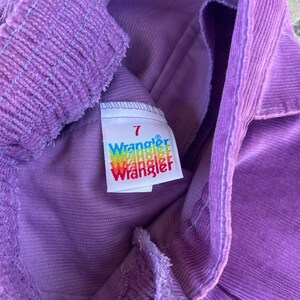 May include: Purple corduroy pants with a white tag that says "7 Wrangler" on it.