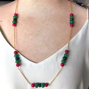 May include: A gold chain necklace with green and red beads. The beads are faceted and have a polished finish.
