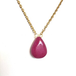 May include: A gold chain necklace with a teardrop-shaped pendant made of pink gemstone.