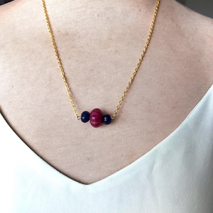 May include: A gold chain necklace with a pink and two blue beads.