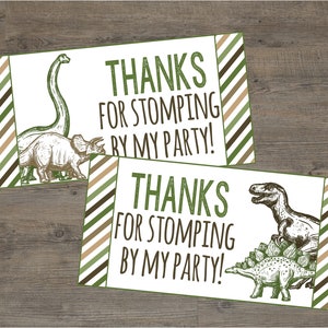 Könnte beinhalten: Zwei bedruckbare Dankeschön-Etiketten mit Dinosaurier-Motiv. Die Etiketten haben einen grün-braun-weiß gestreiften Hintergrund mit dem Text "Danke, dass du auf meiner Party warst!" und Illustrationen von Dinosauriern.