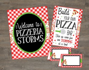 May include: A red and white checkered sign with the text "Welcome to Pizzeria Storms" in a black circle with a green border. A smaller sign with the text "Build Your Own Pizza Bar" and a pizza slice graphic. Two blank place cards with a pizza slice graphic.