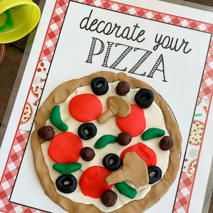 Pode incluir: Um cart&atilde;o branco com uma borda xadrez vermelha e branca, o texto "decore sua pizza" em fonte cursiva preta e uma pizza de massa de modelar com pepperoni vermelho, piment&otilde;es verdes, cogumelos marrons e azeitonas pretas.