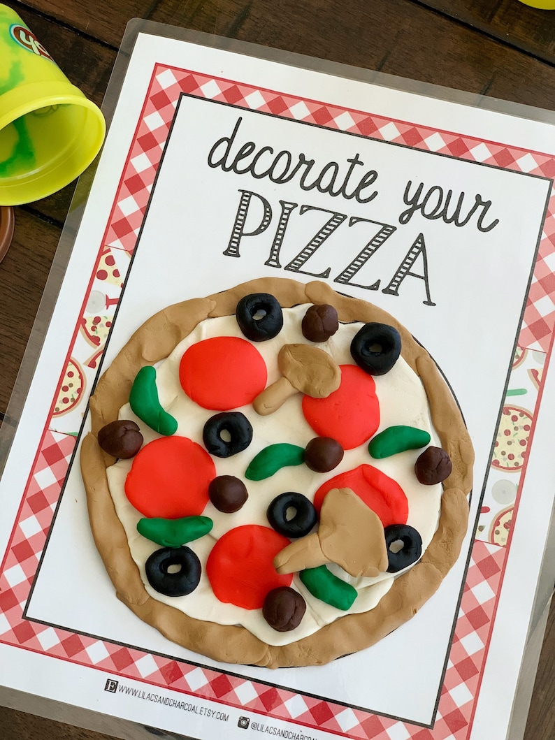 Pode incluir: Um cart&atilde;o branco com uma borda xadrez vermelha e branca, o texto "decore sua pizza" em fonte cursiva preta e uma pizza de massa de modelar com pepperoni vermelho, piment&otilde;es verdes, cogumelos marrons e azeitonas pretas.