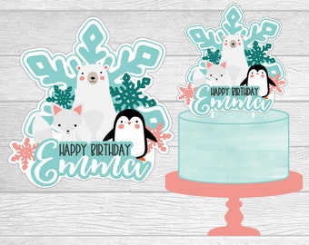 May include: A cake topper featuring a polar bear, a fox, and a penguin with a snowflake design. The topper says "Happy Birthday Emma".