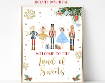 May include: A printable sign with a gold frame featuring a Nutcracker theme. The sign has a white background with gold snowflakes and stars. The text reads "Welcome to the Land of Sweets" in gold lettering. There are five Nutcracker characters, including a mouse king, a ballerina, and a soldier, all in colourful costumes.