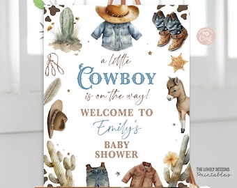 May include: A white baby shower sign with the text "a little COWBOY is on the way! WELCOME TO Emily's BABY SHOWER". The sign is decorated with cowboy hats, boots, cacti, and a brown and white donkey.