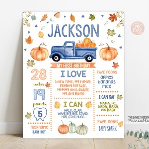 Puede incluir: Un cartel ilustrado de primer cumpleaños azul y naranja para un niño llamado Jackson. El cartel incluye su edad, peso, altura, comidas favoritas, actividades y un apodo. El cartel presenta una camioneta azul con calabazas en la parte trasera.
