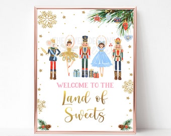 May include: A white printable sign with a gold frame featuring a Nutcracker theme. The sign has a pink and gold welcome message that reads "Welcome to the Land of Sweets". The sign features a mouse, a ballerina, a nutcracker, and a princess.