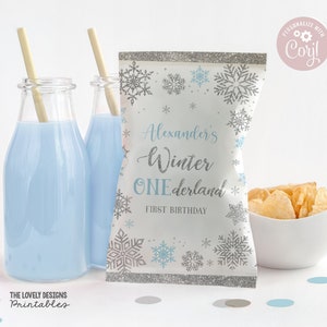 May include: A white and silver snowflake-themed party favor bag with the text "Alexander's Winter Wonderland First Birthday".