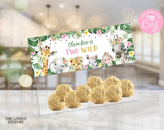 May include: A white and green party favor bag with a jungle animal theme. The bag has a label that says "Olivia Rose is Two Wild" with a giraffe, elephant, lion, rhino, and monkey. The bag is filled with gold chocolate candies.