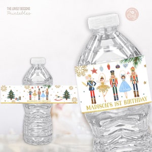 May include: Water bottle label featuring a Nutcracker theme with a gold background and a white border. The label features a Nutcracker, a ballerina, a mouse king, and other characters from the Nutcracker story. The text on the label reads "Madison's 1st Birthday".