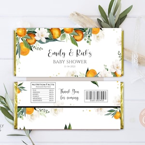 May include: Baby shower candy bar wrapper design. Features orange fruit and white floral arrangements with green leaves. The text reads "Emily & Rick's BABY SHOWER 11-14-2021" and "Thank You for coming".