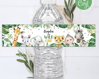 Op de afbeelding: Waterfleslabel met een jungle thema. Het label toont een giraffe, olifant, leeuw, aap en zebra met groene bladeren en gouden accenten. De tekst op het label luidt "Brayden is a Wild One".