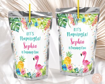 May include: Two silver juice boxes with a tropical theme. The boxes have a white label with the text "Let's Flamingle! Sophia is turning One" and a pink flamingo illustration. The boxes are decorated with green leaves, pink flowers, and colorful confetti.