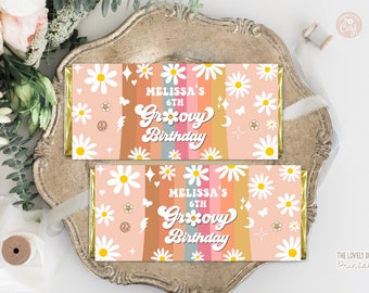 May include: Two candy bar wrappers with a groovy birthday theme. The wrappers feature a peach background with daisies, peace signs, and the text "Melissa's 6th Groovy Birthday" in a retro font. The bars are on a decorative tray.