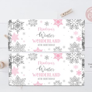 May include: Two printable favor tags with a winter wonderland theme. The tags feature a white background with pink and silver snowflakes and the text "Madison's Winter Wonderland 4th Birthday".