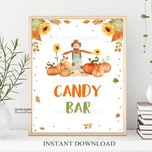 May include: A printable sign with a cartoon scarecrow and pumpkins, with the text "Candy Bar" in orange and green letters. The sign is decorated with fall leaves and sunflowers.