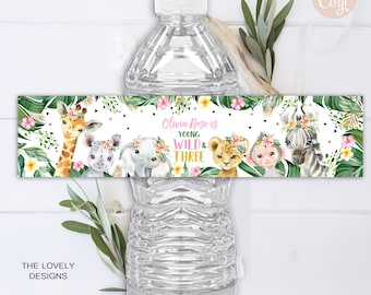 Puede incluir: Etiqueta de botella de agua con temática de la jungla. La etiqueta presenta una jirafa, una cebra, un elefante, un mono y un león con diademas florales. El texto de la etiqueta dice "Olivia Rose is Young Wild & Three".