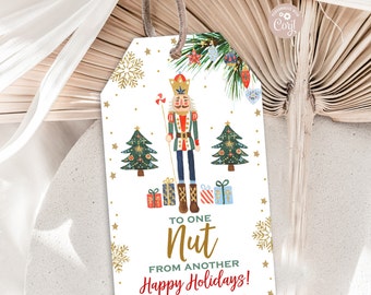 May include: A white gift tag with a nutcracker illustration, Christmas trees, and gold snowflakes. The text reads "To one Nut From another Happy Holidays! From: The Carters".
