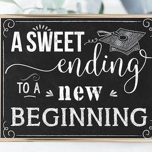 May include: A black chalkboard sign with gold trim and white text that reads "A sweet ending to a new beginning". A graduation cap is drawn in the upper right corner of the sign.