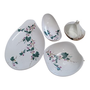 May include: Set of four white ceramic dishes with a floral design. The dishes feature a green and pink floral pattern with a branch design. The dishes are perfect for serving snacks, appetizers, or desserts.