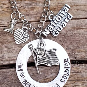 May include: Silver necklace with a charm that says "My heart belongs to a soldier" with a small American flag charm, a boot charm, and a charm that says "National Guard".