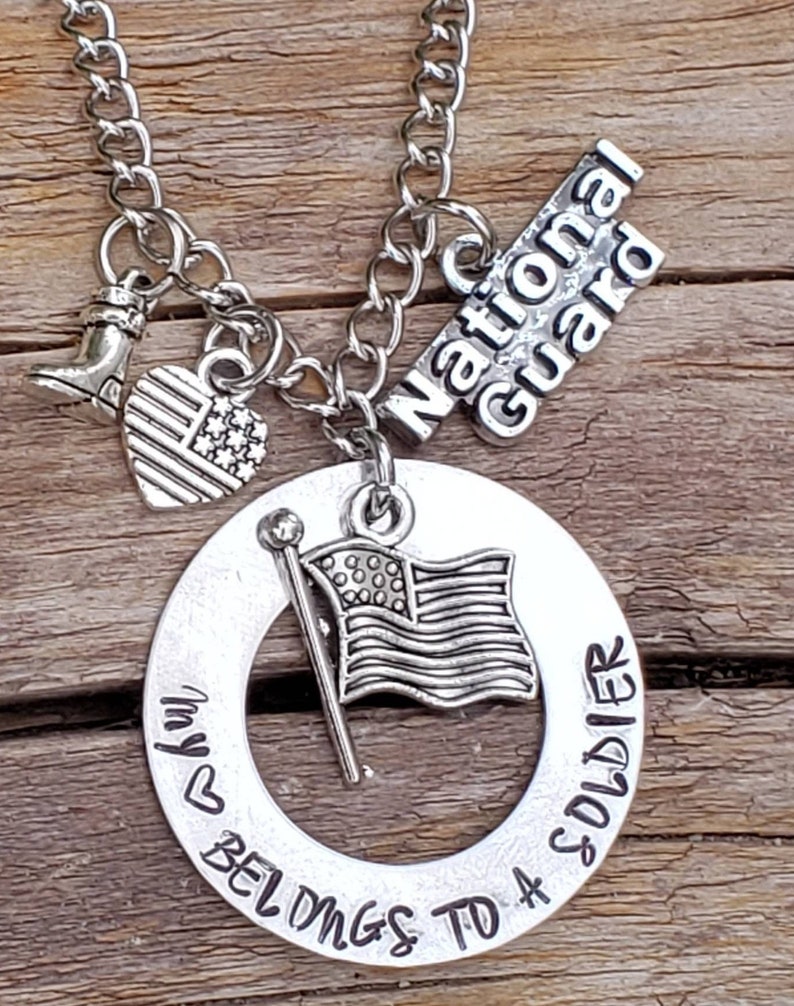 May include: Silver necklace with a charm that says "My heart belongs to a soldier" with a small American flag charm, a boot charm, and a charm that says "National Guard".