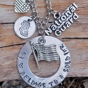 May include: Silver necklace with charms, including a heart with an American flag, a boot, a flag, and a circle charm that says "My heart belongs to a soldier". The charm with the flag also says "National Guard".