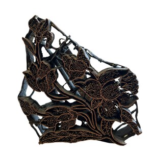 May include: A dark brown wooden block print stamp featuring an intricate floral design with multiple blooming flowers and leaves. The surface of the raised relief pattern is textured with small dots, creating a detailed botanical motif for printing.