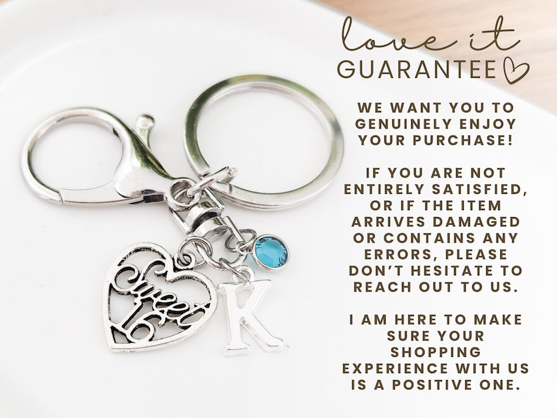 May include: Silver-toned keychain with a heart-shaped charm that says "Sweet 16". The keychain also includes a letter "K" charm and a small blue gemstone. The keychain is attached to a clasp and a key ring.