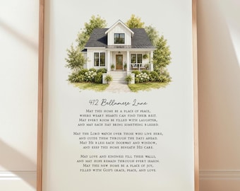 May include: A framed wall art print featuring a watercolor illustration of a white house with a dark roof, surrounded by green trees and shrubs. Below the house, the text reads 412 Bellamere Lane followed by a multi-line house blessing poem.