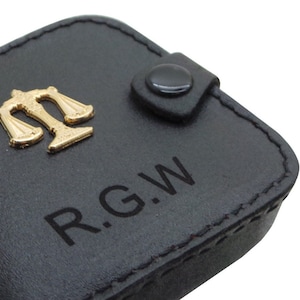 May include: Black leather key chain with a gold scales of justice charm and the initials "R.G.W." engraved on the front.