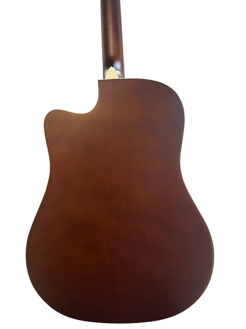 Puede incluir: Parte trasera de una guitarra ac&uacute;stica con acabado marr&oacute;n oscuro. El cuerpo de la guitarra tiene forma redondeada con un corte, y el m&aacute;stil es de un tono marr&oacute;n m&aacute;s oscuro. El clavijero es visible en la parte superior.