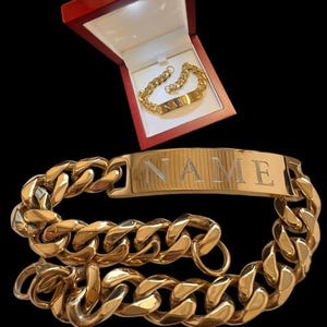May include: A gold chain bracelet with a nameplate that says "NAME". The bracelet is in a red velvet box with a gold chain bracelet inside.