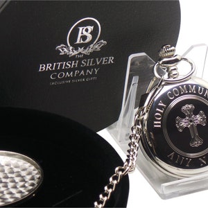May include: Silver pocket watch with a black face and a cross design. The watch is engraved with the words "Holy Communion" and "Any Name". The watch comes in a black box with a silver logo that reads "The British Silver Company, Exclusive Silver Gifts".
