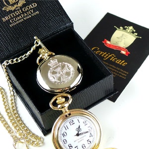 Pode incluir: Relógio de bolso dourado com um mostrador branco e marcadores de hora romanos pretos. O relógio tem uma corrente dourada e está numa caixa preta com um certificado. O certificado diz "Certificado" e "Nuby certifica que a peça foi submetida a uma classificação rigorosa em vários"