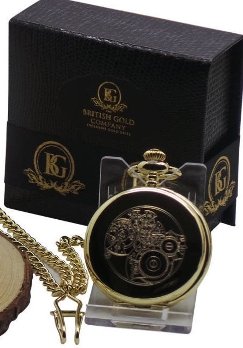 May include: Gold pocket watch with a gold chain and a black box with the text "The British Gold Company Exclusive Gold Gifts".