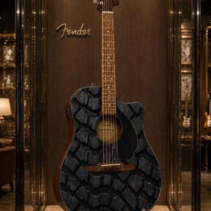 K&ouml;nnte beinhalten: Akustikgitarre mit einem einzigartigen schwarzen Steinmuster auf dem Korpus, pr&auml;sentiert in einer Glasvitrine. Das Fender-Logo ist auf der Kopfplatte und dem Holzgrund zu sehen. Die Gitarre hat einen dunkelbraunen Hals und ein schwarzes Schlagbrett.