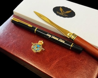 May include: A red leather box with a gold pen, a letter opener, and a gold pin with a blue and gold emblem. The box has the text "The Luxury Vault" on it.