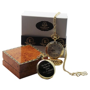 Peut inclure: Montre de poche dorée avec une chaîne dans un coffret en bois. Le cadran de la montre comporte des chiffres romains et les mots "British Gold Company". Le dos de la montre est gravé avec le texte "The day you became my daddy VII-11-MMXVI".