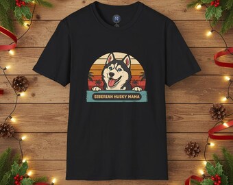 Könnte beinhalten: Schwarzes T-Shirt mit einem Retro-Design eines Siberian Husky-Hundes mit blauen Augen und herausgestreckter Zunge, vor einem Sonnenuntergangshintergrund. Der Text "SIBERIAN HUSKY MAMA" befindet sich unter dem Hund. Das T-Shirt ist von Weihnachtsdekorationen umgeben.