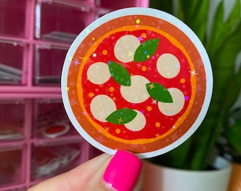 May include: A round sticker featuring a pizza design. The pizza has a red sauce base, white mozzarella cheese, and green basil leaves. The sticker has a white border and a holographic, glittery effect.